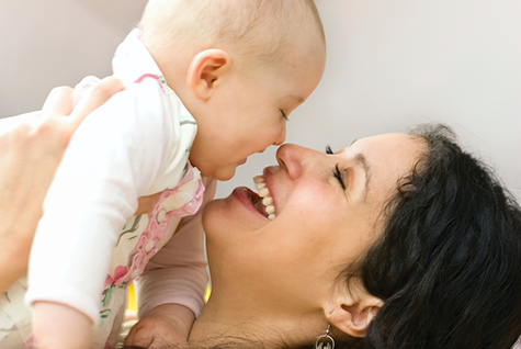 a smilimg woman holding a baby